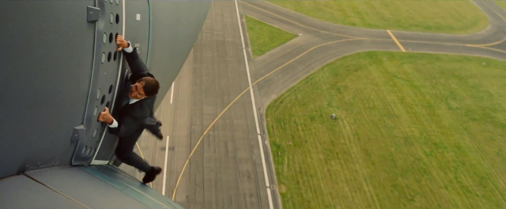 Ethan Hunt (Tom Cruise). Hanging from an aircraft.